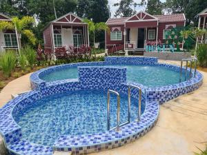 a swimming pool with blue tiles in front of a house at Singgah Dusun Zahra in Kampong Perak
