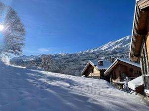 a snow covered road next to a house with mountains in the background at Chalet Mademoiselle in Les Allues