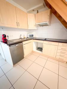 a kitchen with wooden cabinets and a sink and a dishwasher at À Quelques pas de la gare - Duplex in Sartrouville