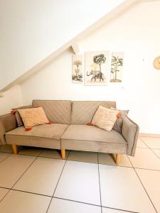a couch in a living room with paintings on the wall at À Quelques pas de la gare - Duplex in Sartrouville