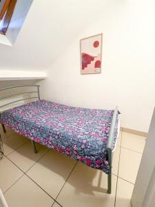 a small bed in a room with a floral bedspread at À Quelques pas de la gare - Duplex in Sartrouville