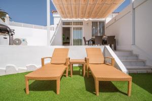 two chairs and a table on a patio with grass at Nice Bungalow with Two Bedrooms in Adeje