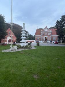a large building with a monument in the middle of a yard at Herregårdslejlighed in Vrå