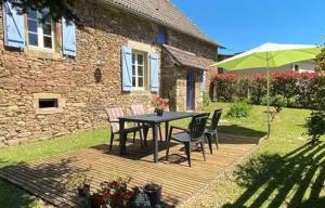 a table and chairs on a deck in front of a house at Gîte Pierre, Beynat, Corrèze in Beynat