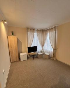 an empty living room with a television and curtains at PENSIUNEA UNO in Timişoara