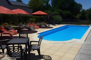 a swimming pool with chairs and tables and umbrellas at Gîte Pierre, Beynat, Corrèze in Beynat