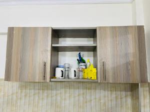 a kitchen cabinet with a bunch of items in it at Haven one bedroom in Busia