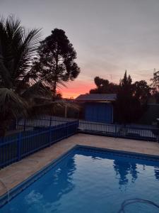 a swimming pool in front of a fence with a sunset at Recanto Vila Madalena in Caçapava