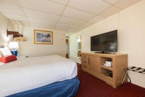 a hotel room with a bed and a flat screen tv at Fireside Inn and Suites Bangor in Bangor