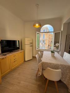 a kitchen with a table and a refrigerator and a window at Appartamento Bixio sul porto in Sanremo