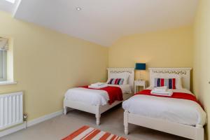 a bedroom with two beds with red and white sheets at 3 Bed in Knodishall oc-wbco in Aldringham