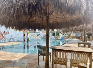 a table and chairs under a straw umbrella next to a swimming pool at Juscelino Pousada lazer in Tibau