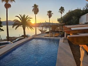 a swimming pool with a view of the water and palm trees at Infinity Blue Korčula in Korčula