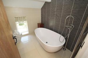 a bathroom with a white tub and a toilet at 4 Bed in Gower oc-hh471 in Llanmadoc +31 photos