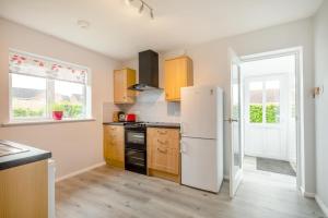 a kitchen with a white refrigerator and wooden cabinets at 2 Bed in Reedham oc-2378 in Haddiscoe +13 photos