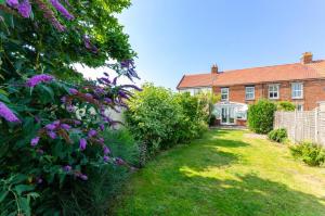 a garden with purple flowers in front of a house at 3 Bed in Winterton-on-Sea oc-2205 in Winterton-on-Sea