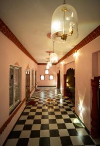 a hallway with a checkerboard floor and a chandelier at Fort Jangaldhar in Bikaner +2 photos