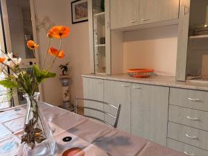 a kitchen with a table with orange flowers in a vase at Baia Incantata in Baia Verde