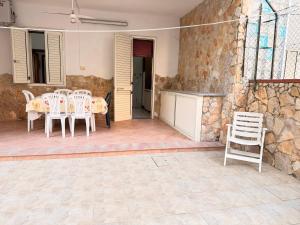 a patio with white chairs and a table and a stone wall at Baia Incantata in Baia Verde +37 photos