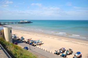 a beach with a group of chairs and a pier at 4 Bed in Cromer oc-1942 in Cromer