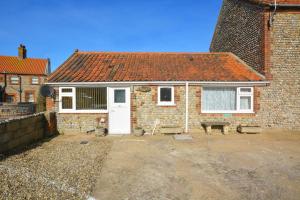 a brick house with a white door and two benches at 2 Bed in Mundesley oc-673 in Mundesley