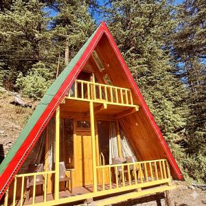 a small house with a red and green roof at Pinehill cottage in Jibhi