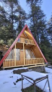 a frame cabin with a table in the snow at Pinehill cottage in Jibhi