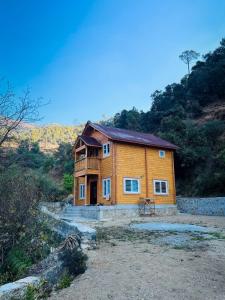 a wooden house in the middle of a field at Samlaun Chalet and Retreat in Kanatal