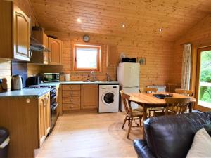 a kitchen and dining room with a table and a refrigerator at 3 Bed in Glenfinnan oc-cabin in Glenfinnan