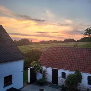 two white buildings with red roofs with a sunset in the background at Lysbjerggård in Faaborg