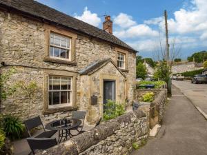 a stone cottage with a table and chairs in front of it at 2 Bed in Matlock oc-77632 in Brassington +10 photos