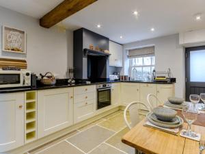 a kitchen with white cabinets and a wooden table at 2 Bed in Matlock oc-77632 in Brassington