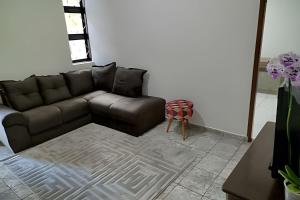 a living room with a brown couch and a table at Refúgio Hostel Unidade 3 in Bauru