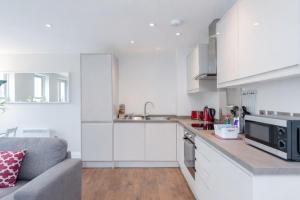 a white kitchen with a couch and a microwave at Roomspace Serviced Apartments - Trinity House in Reigate