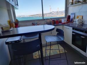 a kitchen with a counter with two stools and a window at La Goelette 4 in Toulon +2 photos