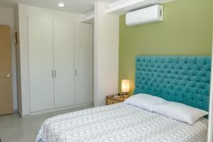 a bed with a blue headboard in a room at Depto. 2 rec. en Playa Mocambo in Boca del Río +65 photos