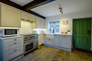a kitchen with white cabinets and a green door at 3 Bed in Kelling oc-w27424 in Kelling