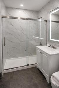 a white bathroom with a shower and a sink at Cabana Hotel Yankee Stadium in Bronx