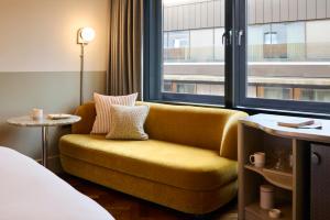 a yellow couch in a hotel room with a window at The Hoxton, Shoreditch in London