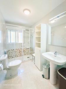a white bathroom with a toilet and a sink at Apartamento Mardevela in Sanxenxo +45 photos