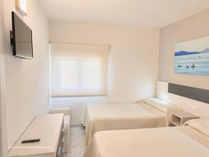 a hotel room with two beds and a flat screen tv at Apartamento Mardevela in Sanxenxo