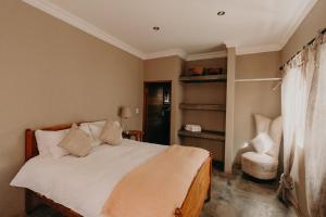 a bedroom with a white bed and a chair at The Nutcracker Homestead in Venterskroon