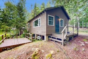 a tiny house in the woods with a wooden ramp at Bay-View Getaway w/ Deck Between Camden & Belfast! in Northport
