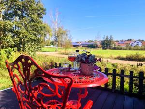 a red table with a glass of wine and a basket of flowers at Ferienhaus Goldgrube - 5 Zimmer - 140qm am Fluss in Katzweiler