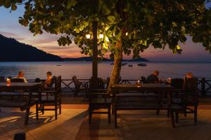 a group of people sitting at tables near the water at Perhentian Island Resort in Perhentian Islands