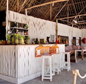 a bar with white tables and chairs in a building at Luwa Beach&Suits in Watamu