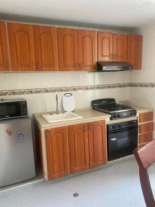 a kitchen with wooden cabinets and a sink and a stove at Siéntete en casa 2 in Pasto