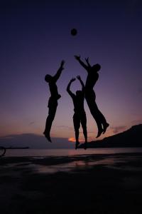 three people jumping in the air on a beach with a frisbee at Perhentian Island Resort in Perhentian Islands