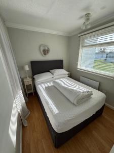 a bedroom with a bed with white sheets and a window at 145, Two bed newly refurbished chalet on Sund0wner Holiday Park - Sleeps 5, pet friendly - Includes bed linen and towels plus electricity in Great Yarmouth