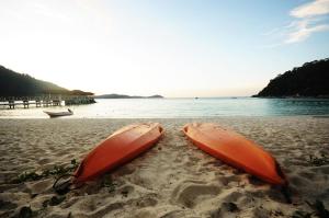 two orange surfboards sitting in the sand on a beach at Perhentian Island Resort in Perhentian Islands